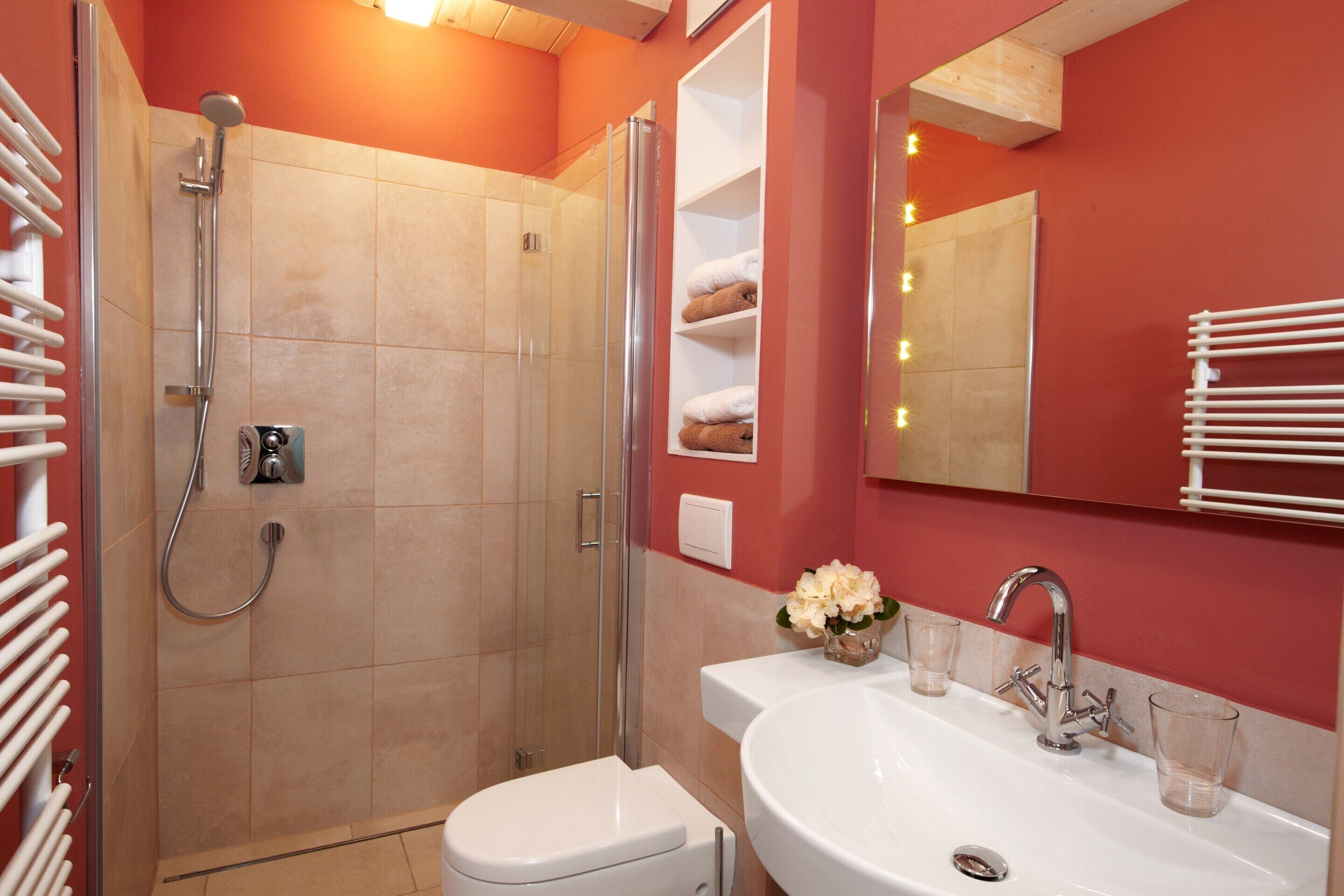 Une salle de bain équipée d’une douche, de toilettes, d’un lavabo et d’un miroir.