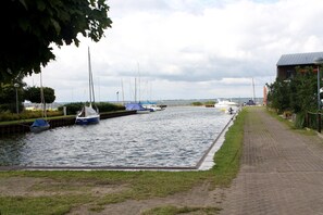 Ein Kanal mit anlegenden Booten, ein gepflasterter Weg und ein Gebäude mit Satteldach.