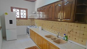 A kitchen with wooden cabinets, a white refrigerator, a sink, and a patterned rug. - Antistoni Cozy  house in beautiful Agros with AC (Agros)