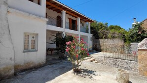 A two-story building with a balcony, a small garden with pink flowers, and a stone wall. - Antistoni Cozy  house in beautiful Agros with AC (Agros)