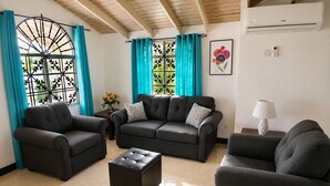 A living room with a sofa set, a coffee table, and a lamp. - 2BR Garden Suite – Minutes from a Glowing Lagoon (Falmouth)