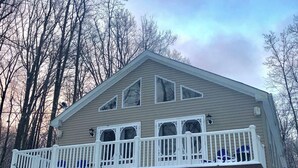 Ein zweigeschossiges Haus mit Balkon, Veranda und Garage.