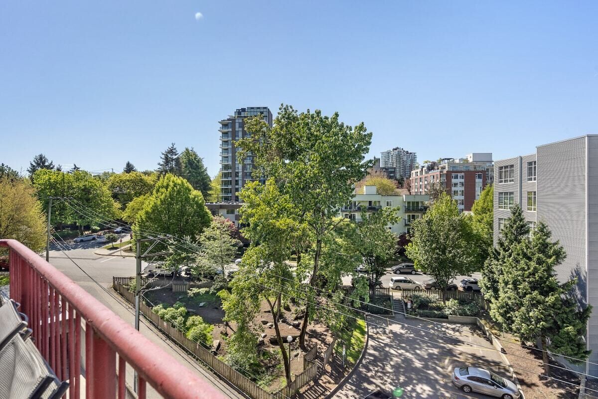 A residential area with multiple-story buildings, trees, and parked cars.