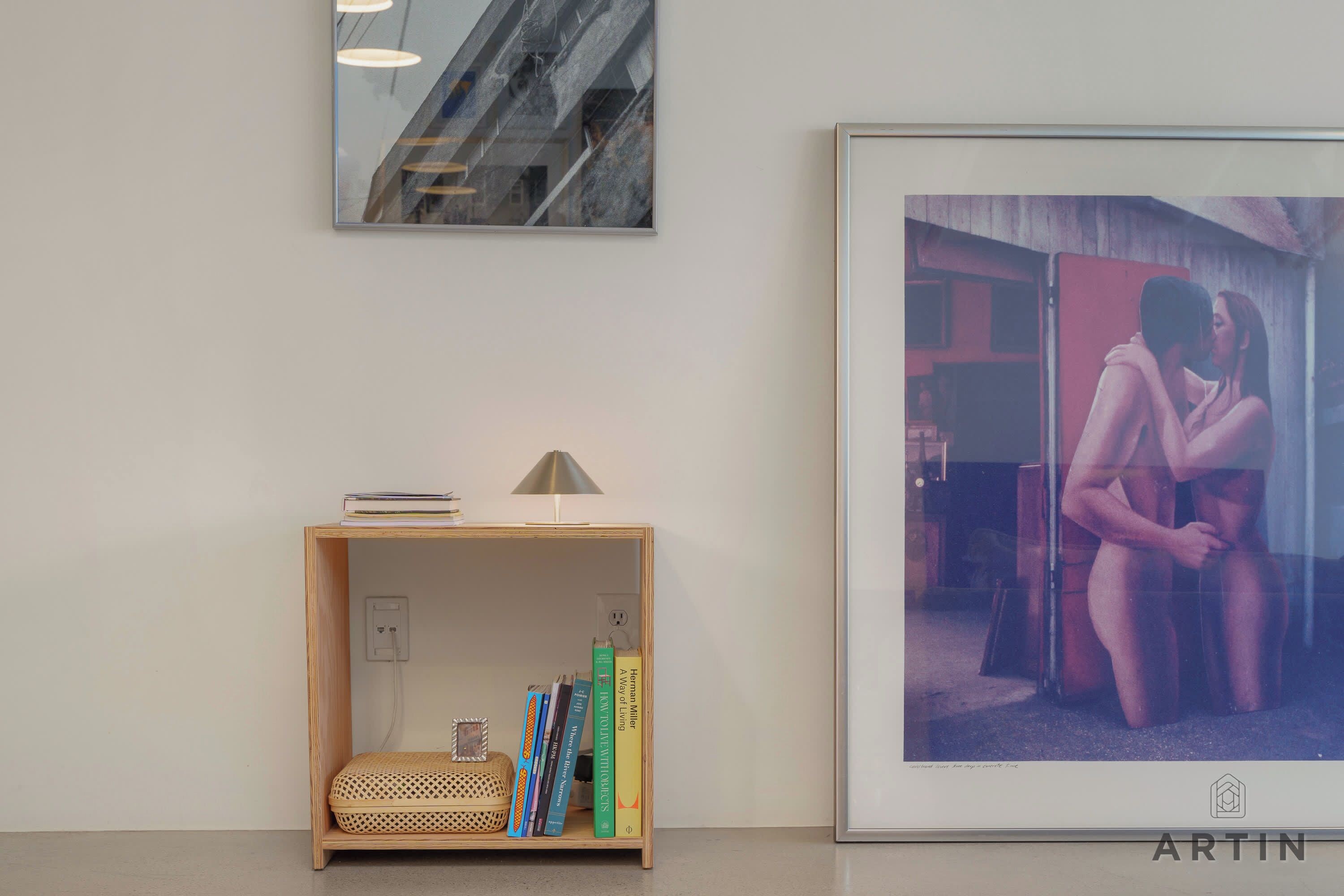 A room with a bookshelf, a framed photograph, and a lamp.