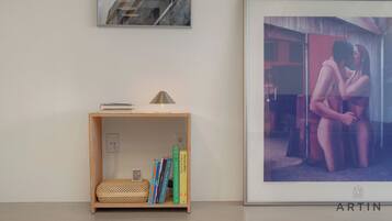 A room with a bookshelf, a framed photograph, and a lamp.