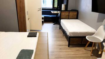 Ein Zimmer mit zwei Betten, einem Schreibtisch, einem Stuhl und einem Fernseher.