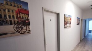 Un pasillo con una puerta marcada '5', una silla de ruedas y la fachada de un edificio.