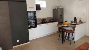 Eine moderne Küche mit einer zentralen Kochinsel, integrierten Geräten und einem Essbereich mit Barhocker.