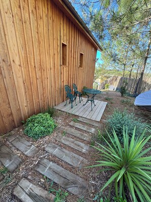 Un bâtiment en bois avec deux chaises en métal vertes et une petite table à l’extérieur.