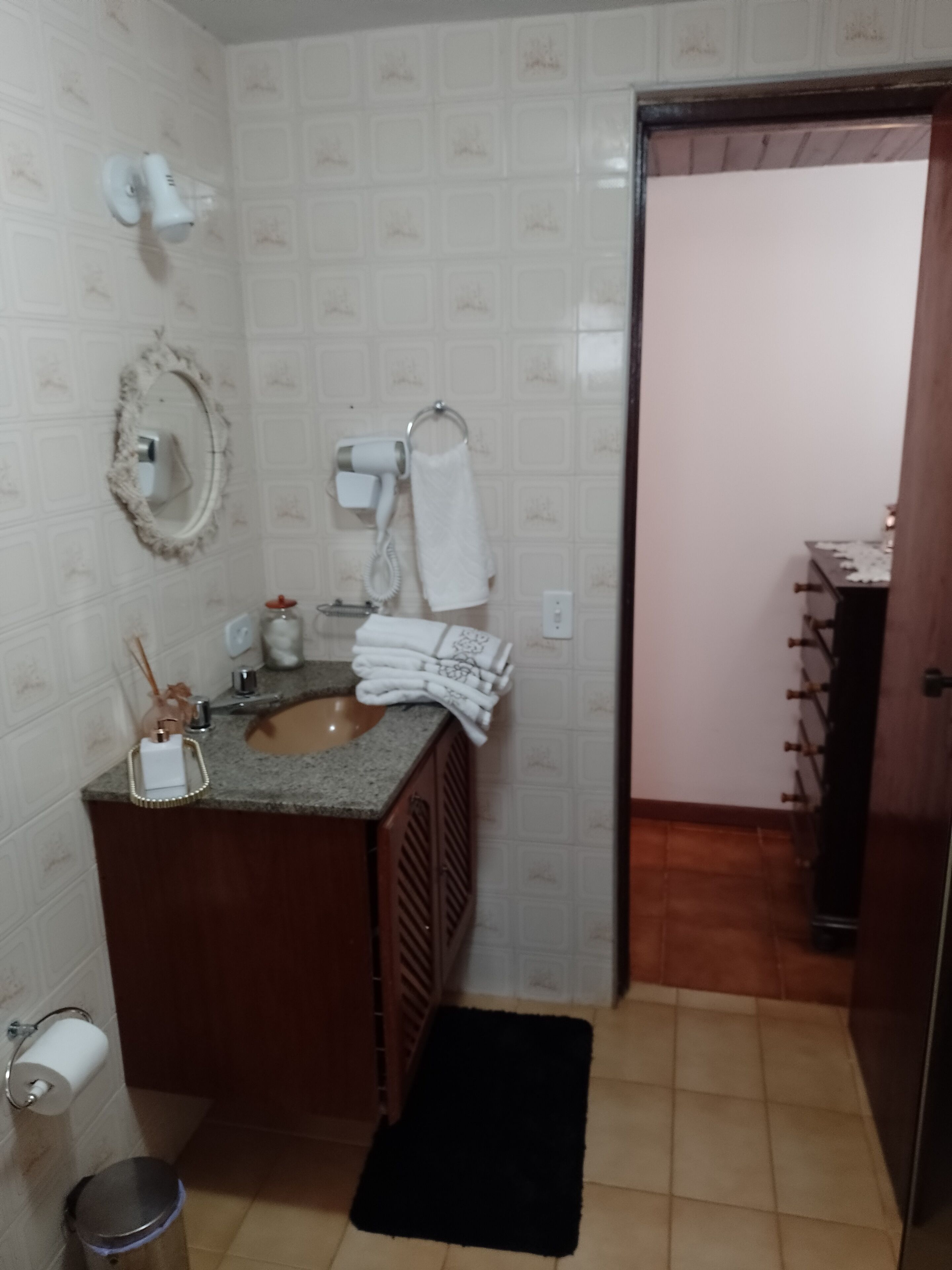 Une salle de bain équipée d’un lavabo, d’un miroir, d’un porte-serviettes et d’une porte donnant sur une autre pièce.