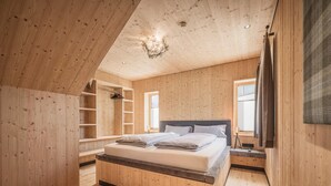 A bedroom with a wooden ceiling, a bed, a nightstand, and built-in shelving. - Your Bright Chalet With Sauna in Bichlbach (Bichlbach)