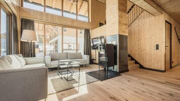 Un interior moderno con suelo de madera, un sofá, un televisor y una escalera.