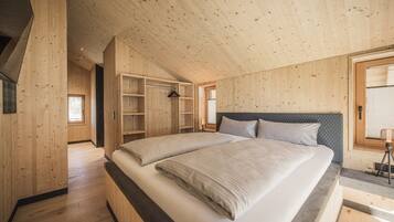 Un dormitorio de madera con una cama grande, estanterías empotradas y un techo inclinado.
