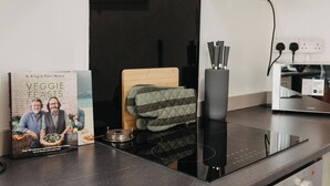 Une cuisine équipée d’une plaque de cuisson à induction noire, d’un four à micro-ondes et d’un livre de recettes intitulé « RECETTES VÉGÉTARIENNES » posé sur le plan de travail.
