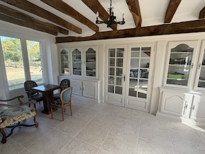 A room with a dining table, chairs, a cabinet with glass doors, and a chandelier. - Family estate with a pool, 2 houses, and spacious outdoor areas - New (La Trimouille)