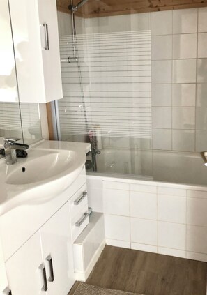 Ein Badezimmer mit weißem Waschbecken, Spiegel und Dusche.