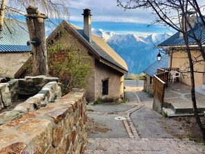 Ein malerisches Dorf mit Steinhäusern, einer Steinmauer und Blick auf einen Berg.