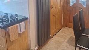 A kitchen with a gas stove, a wooden cabinet, a radiator, and a door with frosted glass panels.