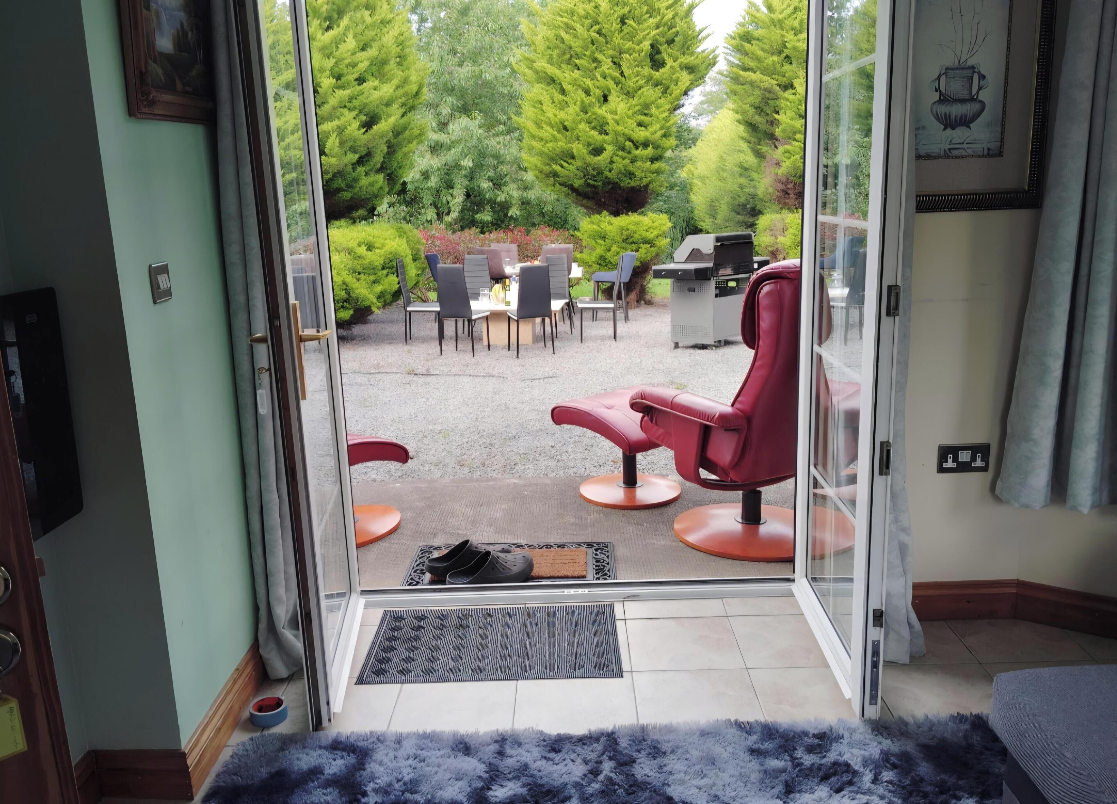 A room with a sliding glass door leading to an outdoor patio area with seating and a grill.