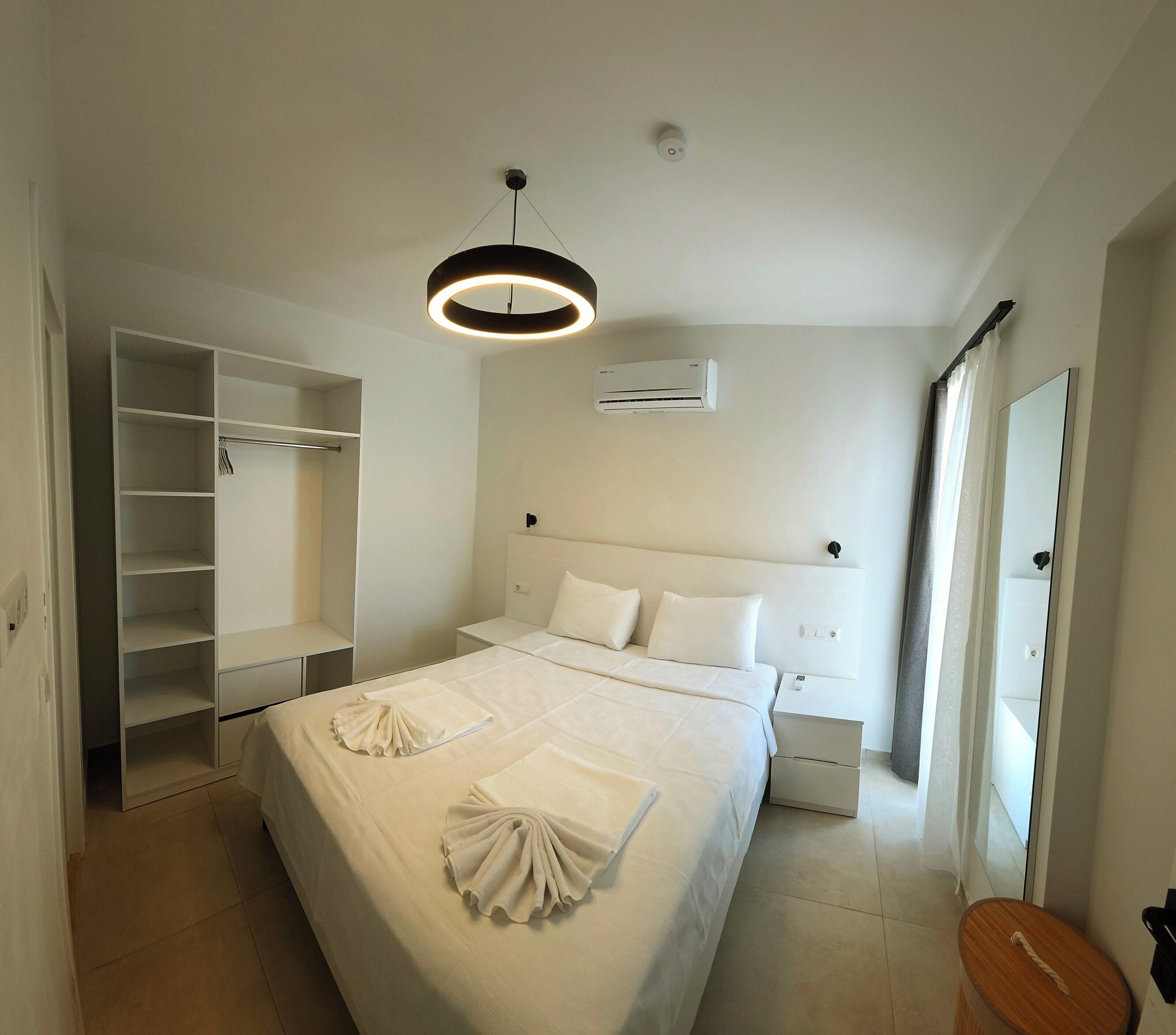 Une chambre d’hôtel comprenant un lit, une armoire, un appareil de climatisation, une table de chevet et un miroir.