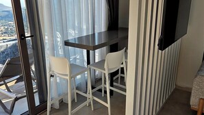 Ett modernt rum med ett matbord, stolar, en tv som är monterad på väggen och ett stort fönster med gardiner.