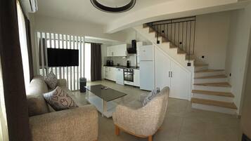 A modern living room with a sofa, coffee table, and a staircase leading to a kitchen area.