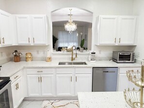 A modern kitchen with white cabinetry, a stainless steel dishwasher, a coffee maker, and a toaster. - Spacious 7-bedroom condo in terrific Kissimmee with AC (Kissimmee)