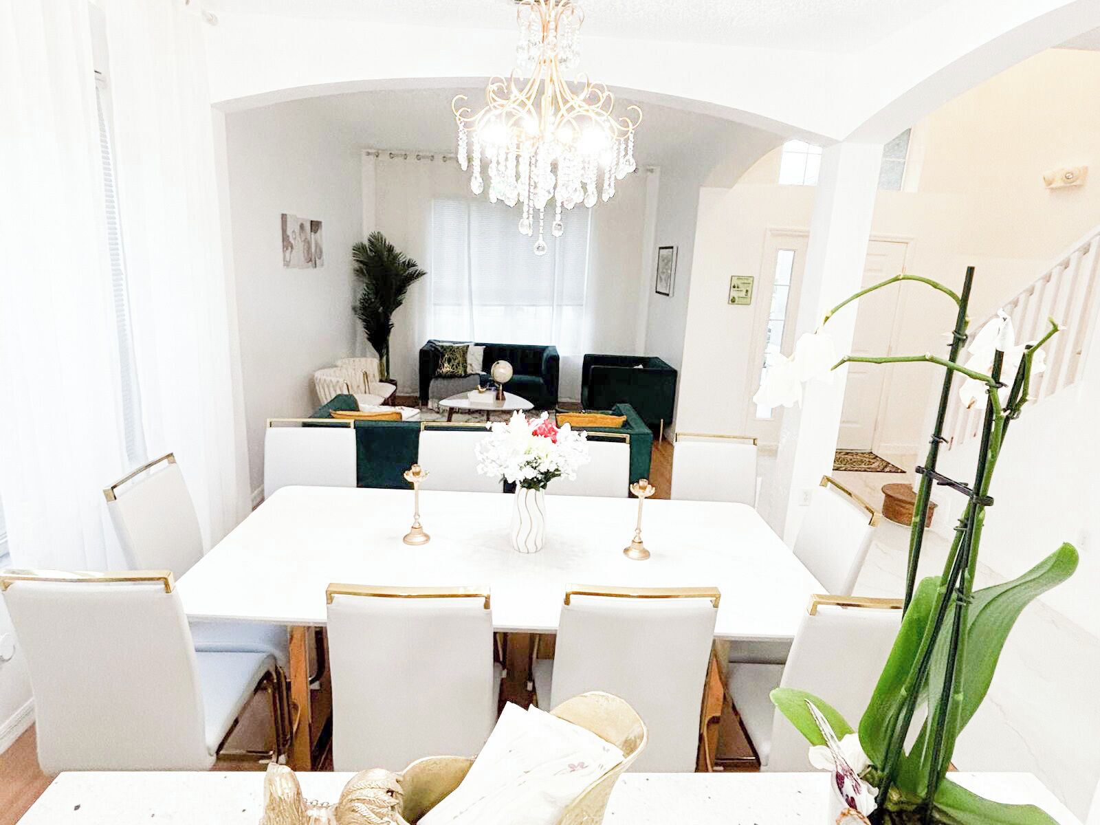 A dining area with a white table, chairs, and a chandelier.