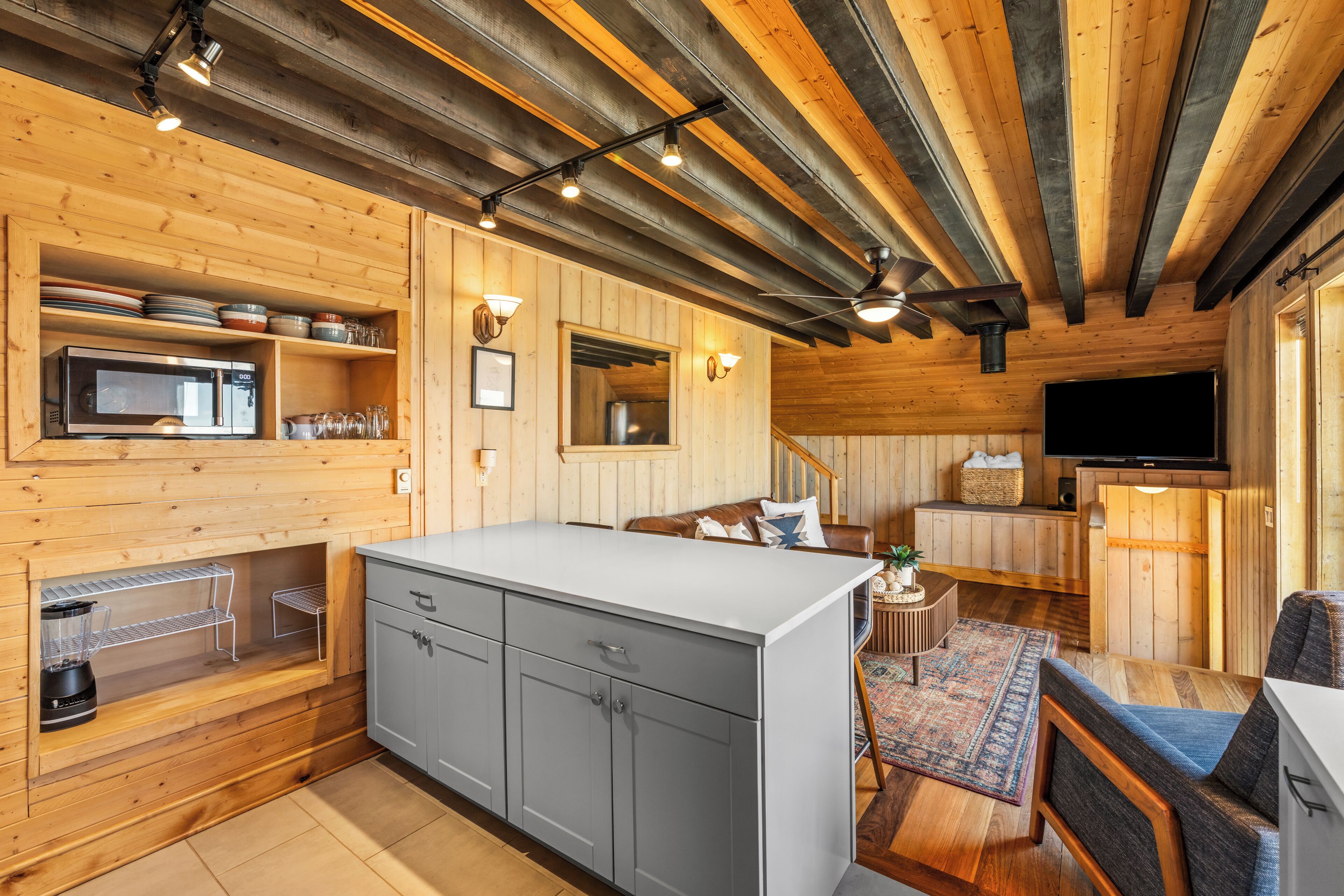L’intérieur d’une cabane en bois comprend une cuisine, un coin repas et un téléviseur.