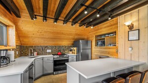 A modern kitchen with wooden beams, a central island, and a seating area.