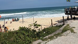 Ein Strand mit Holzzaun, einer Flagge und entspannten Menschen.