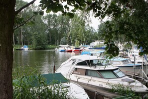 Ein Yachthafen mit angestuften Booten, umgeben von Bäumen und ruhigem Wasser.