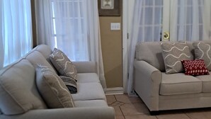 Ein Wohnzimmer mit zwei Sofas, einem großen Bogenfenster und einer Glastür.