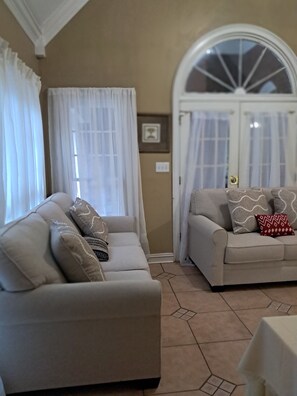 A living room with two sofas, a large arched window, and a door with glass panels. - Quiet community, Family-friendly, ready to move in. 3 bedrooms, 2.5 bathrooms. (Statham)