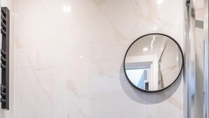 Ein Badezimmer mit Toilette, Waschbecken mit Spiegel und Duschbereich.