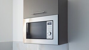 En inbyggd mikrovågsugn med digital display och kontrollpanel, integrerad i ett köksskåp.