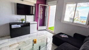 A modern living room with a glass coffee table, black sofa, and a view of the outdoors. - Sea-view apartment in Torremolinos, a 10-minute walk to the beach (Torremolinos)