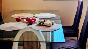 A dining table with placemats, a plate with tomatoes, and a folded napkin, set against a window with a cityscape view. - Sea-view apartment in Torremolinos, a 10-minute walk to the beach (Torremolinos)