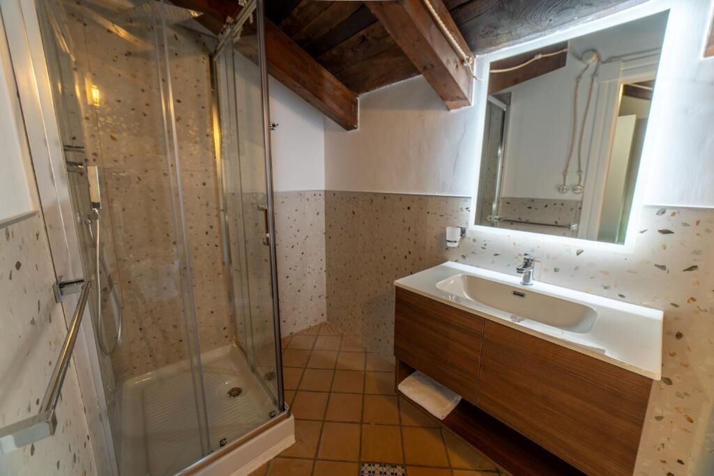 Ein Badezimmer mit Glasdusche, Holzausstattung und einem großen Spiegel.