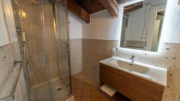Une salle de bain avec une douche à parois de verre, un meuble-lavabo en bois et un grand miroir.