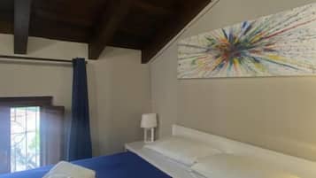 A hotel room with a large bed, a ceiling with exposed beams, a colorful abstract painting on the wall, and a window with curtains.