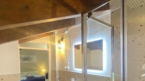 Un baño moderno con cabina de ducha de vidrio, un lavabo y un espejo.