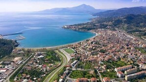 Vista aérea de una ciudad costera con una extensa masa de agua, una montaña al fondo y una zona urbana densamente construida.