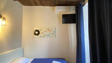 A bedroom with a bed, a wall-mounted artwork, a ceiling fan, and a window with curtains.