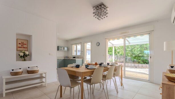 Ein moderner Essbereich mit Holztisch, weißen Stühlen und einer Bank mit Körben.
