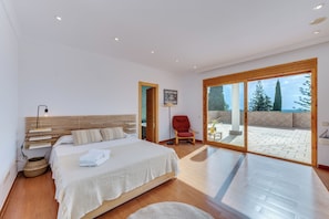 A bedroom with a bed, a chair, a lamp, and a view of the outdoors. - LXR Villa Mirador del Sur, 5 Bedrooms, Ocean Views (Marbella)