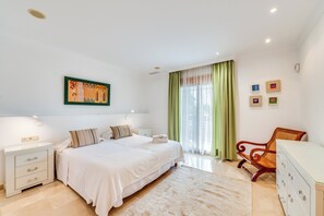 Une chambre à coucher comprenant un lit, des tables de chevet, une chaise et une commode.