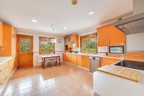 A kitchen with orange cabinets, a wooden dining table, and a dishwasher. - LXR Villa Mirador del Sur, 5 Bedrooms, Ocean Views (Marbella)