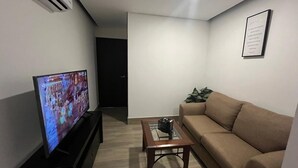 A living room with a flat-screen TV, a wooden coffee table, a beige sofa, and a framed picture on the wall. - Patriota Loft for 2, with amenities and parking (Monterrey)