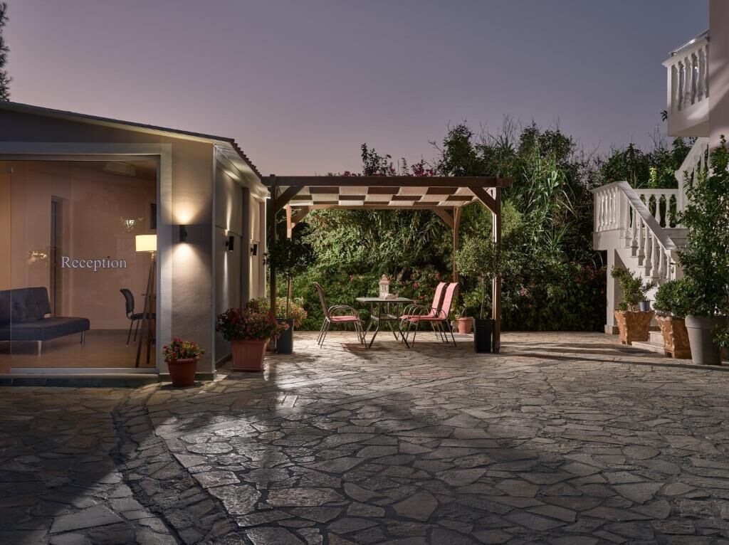 A reception area with a checkered pergola, stone flooring, and potted plants.